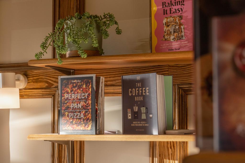 Two books on a shelf, one titled 'Perfect Pan Pizza' and the other 'The Coffee Book'.